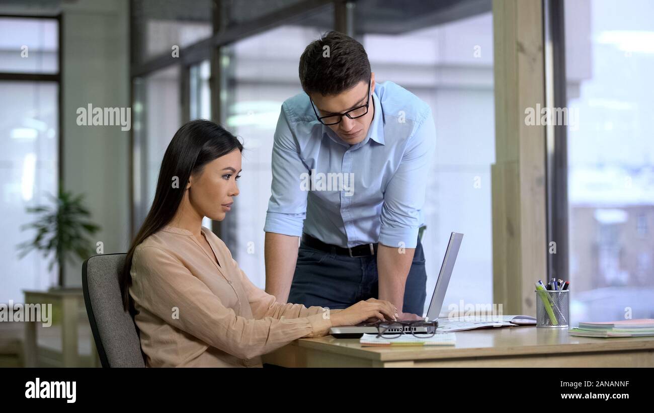 Il boss bello il controllo del lavoro di assistente femmina, i giornalisti che scrivono articolo Foto Stock