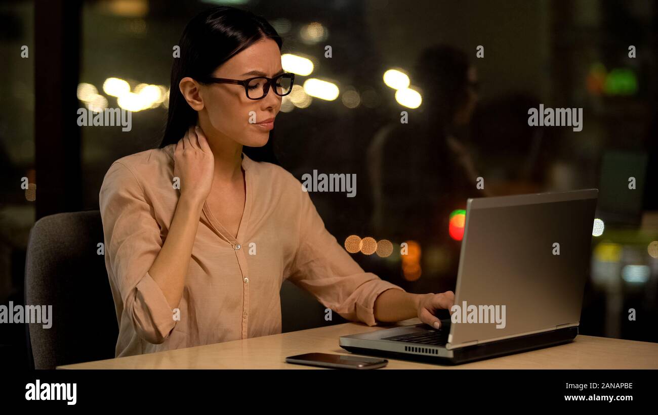 Stanco business lady sensazione di dolore al collo lavorando sul computer portatile durante la notte, la cura della salute Foto Stock