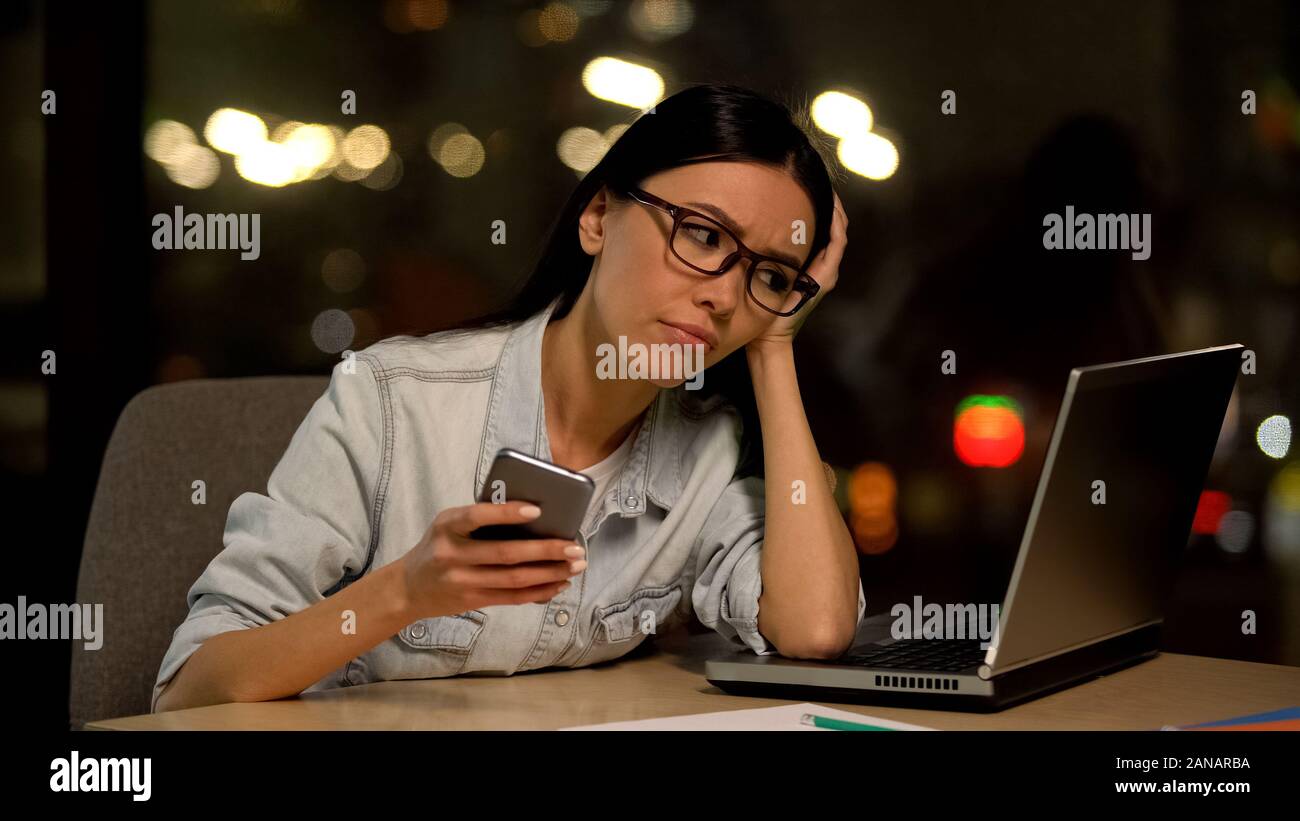 Disattento giovane donna in chat smartphone, evitando il lavoro, l'indifferenza di lavoro Foto Stock