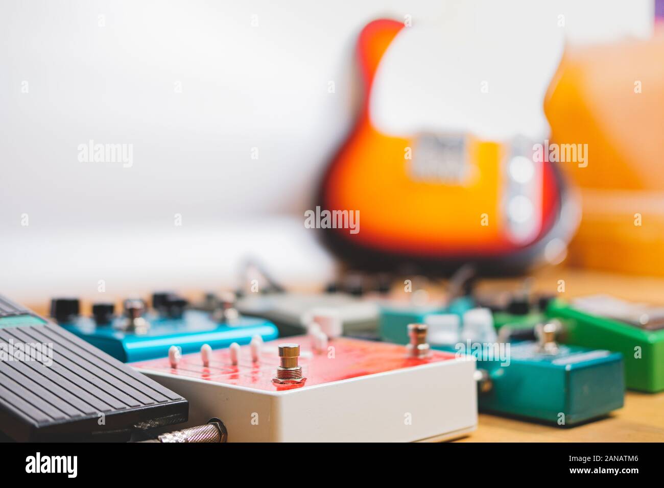 Guitar pedalboard sul pavimento di uno studio di registrazione, chitarra elettrica in background. Generico effetti chitarra su pavimento di legno. Registrazione di chitarra, Foto Stock