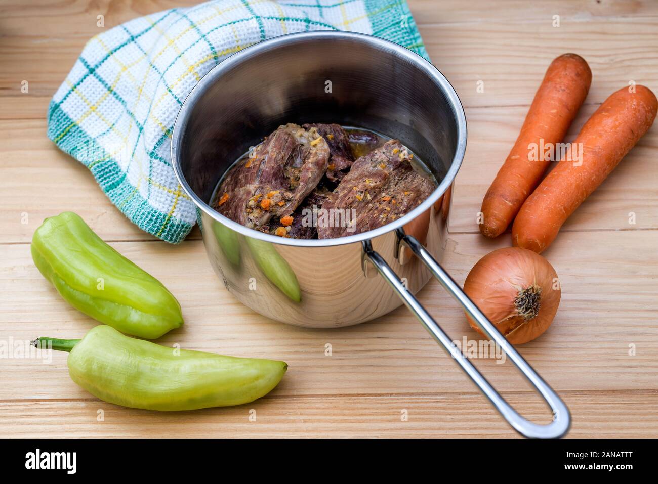 Tradizionalmente le bistecche di manzo in salsa di carote e cipolle offerta come primo piano in una ghisa padella su di un tavolo di legno Foto Stock