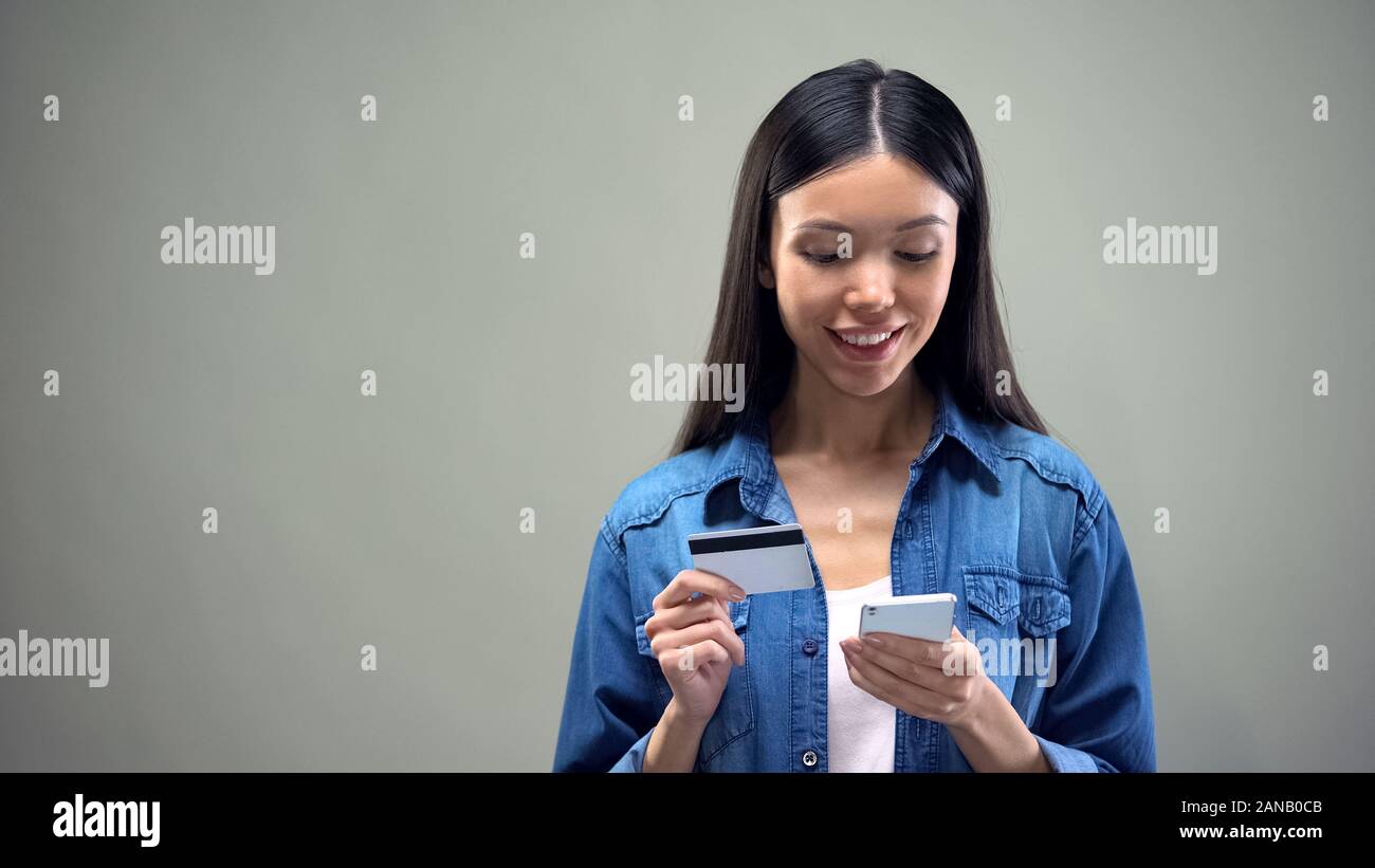 Donna attraente immettendo il numero di carta di credito su smartphone, lo shopping online Foto Stock