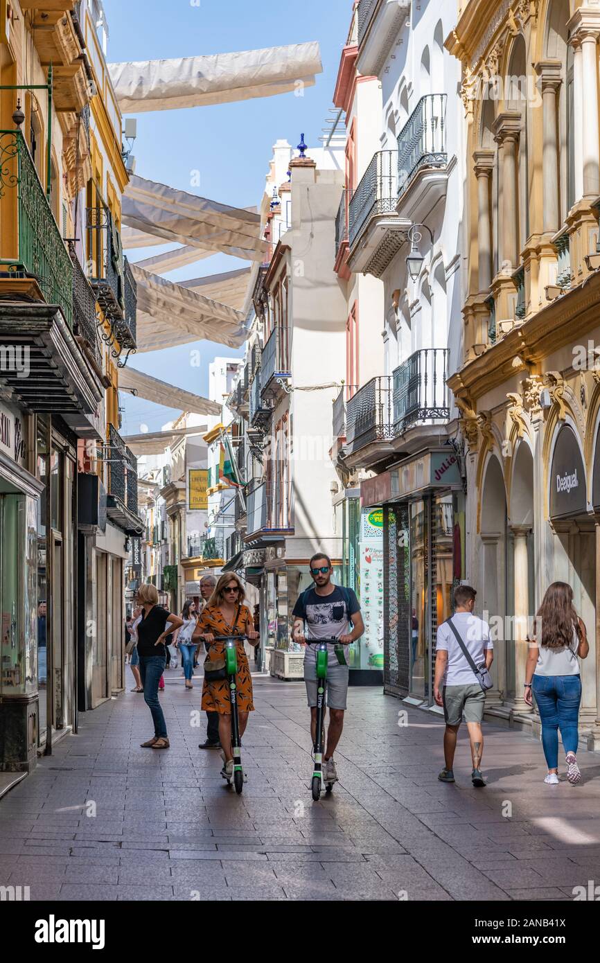 Gli amanti dello shopping sono all'ombra del sole di metà pomeriggio in Calle Sierpes, la principale via pedonale dello shopping di Siviglia. Foto Stock