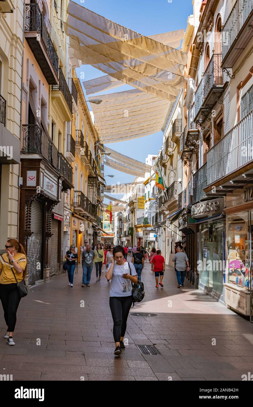Gli amanti dello shopping sono all'ombra del sole di metà pomeriggio in Calle Sierpes, la principale via pedonale dello shopping di Siviglia. Foto Stock