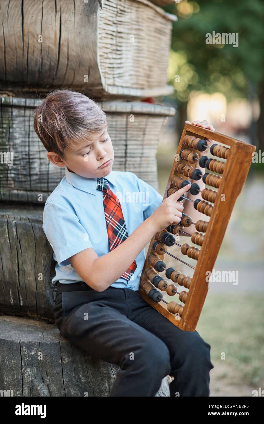 Ragazzo con grandi abacus. Riflessivo schoolboy usando una matematica di calcolo abacus Foto Stock