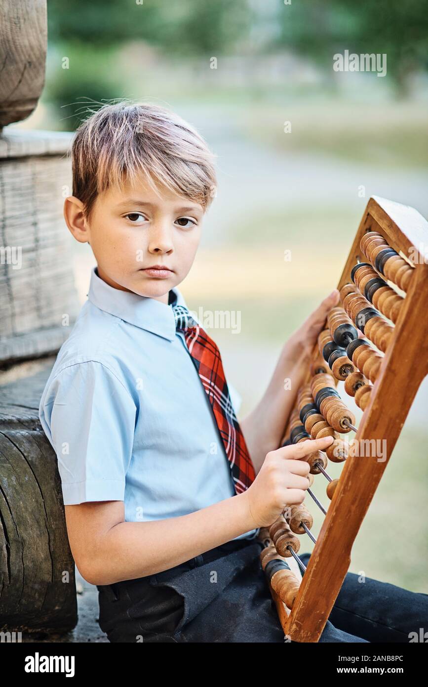 Ragazzo con grandi abacus. Riflessivo schoolboy usando una matematica di calcolo abacus Foto Stock