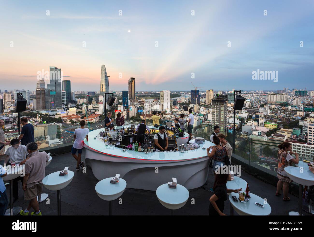 La città di Ho Chi Minh, Vietnam - 17 Marzo 2018: il turista a godere di un drink in un bar sul tetto sopra la skyline di Saigon durante il tramonto in Vietnam la più grande città in modo Foto Stock