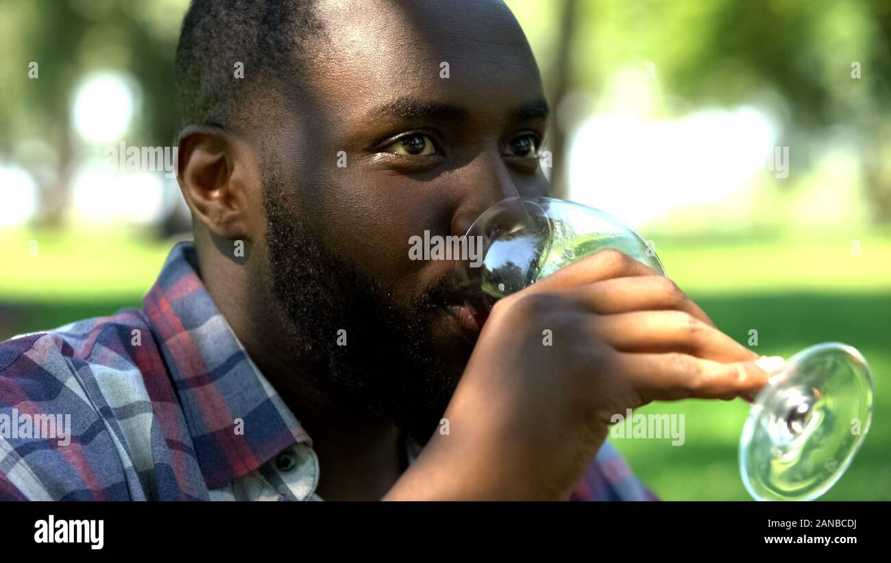 Maschio nero di bere vino, incontro con gli amici nel parco, relax tempo su picnic Foto Stock