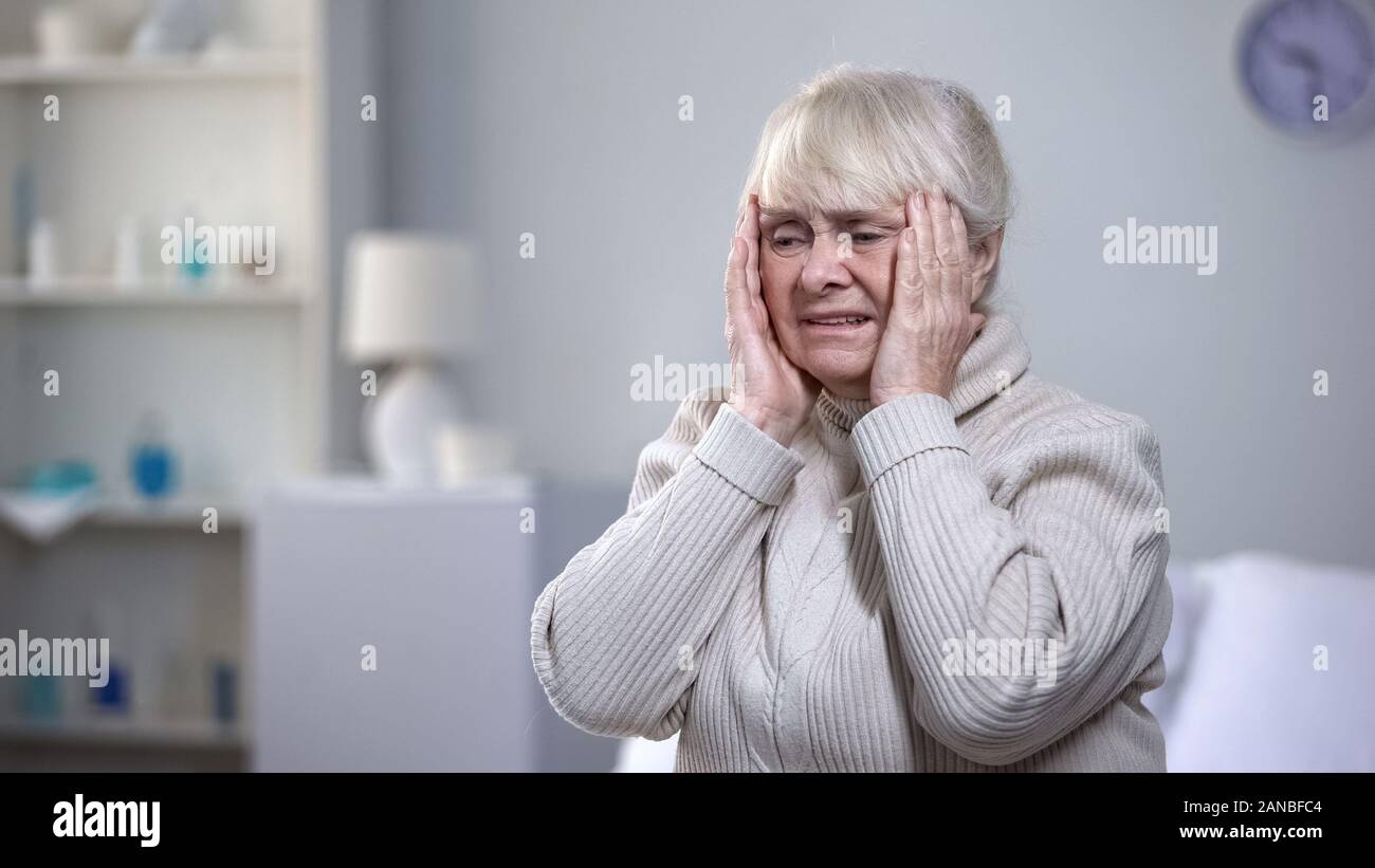 Infelice donna senior tenendo la testa, affetti da emicrania disturbo, salute Foto Stock