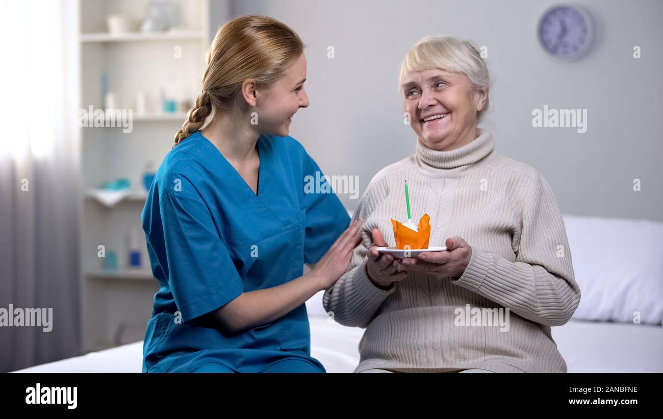 Volunteer festeggia il compleanno con la signora anziana tenendo la torta, cura del paziente Foto Stock
