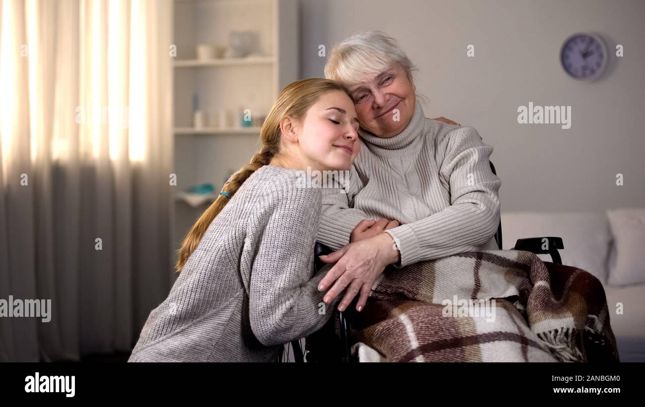 La nipote abbracciando handicappati nonna, famiglia gentilezza, volontariato Foto Stock