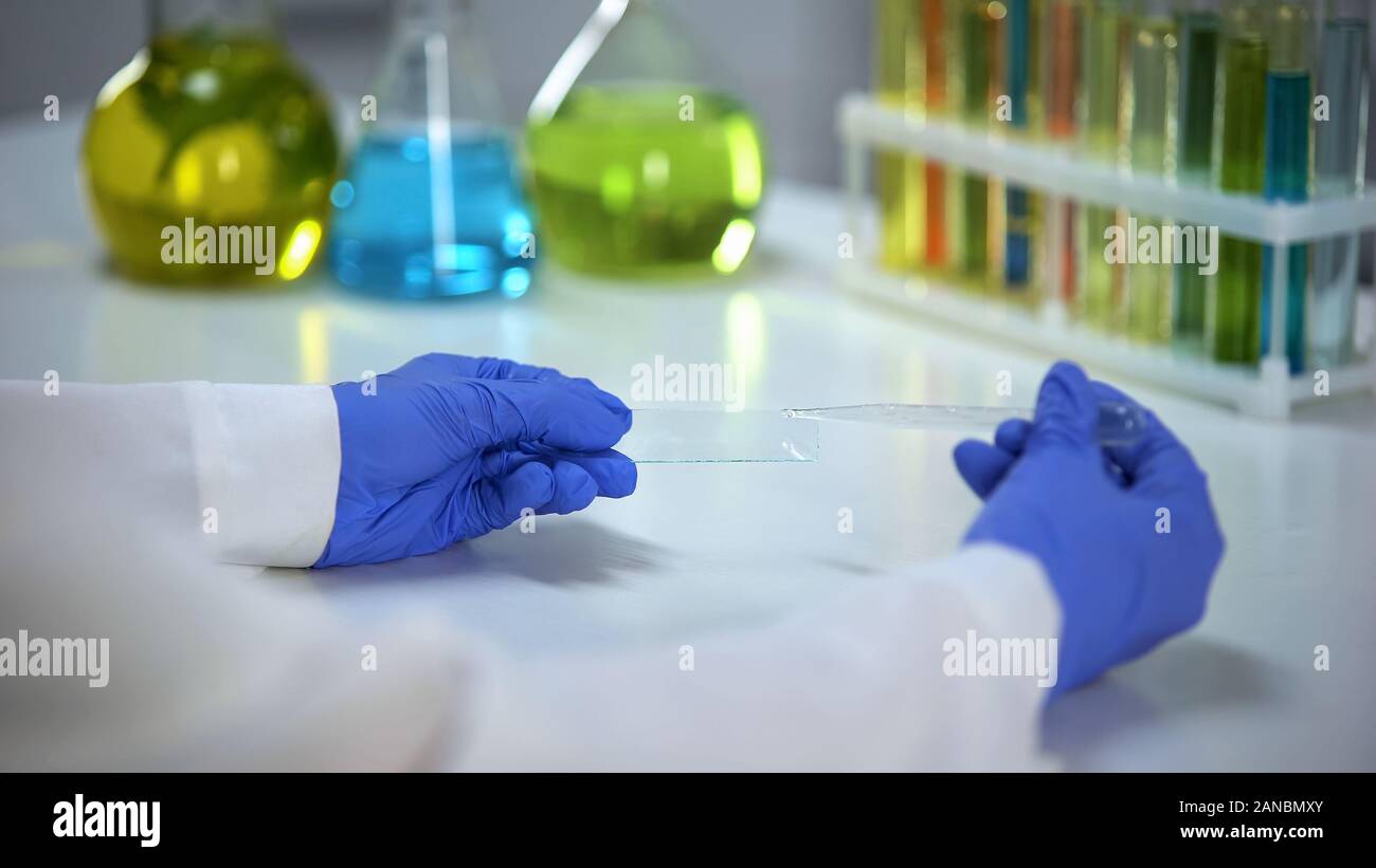 Lo scienziato prova di tenuta vetro con gocce di liquido detergente, laboratorio di sviluppo Foto Stock