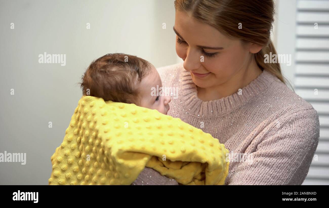 Giovane madre holding adorabili baby in armi, alimentazione artificiale, cura del neonato Foto Stock
