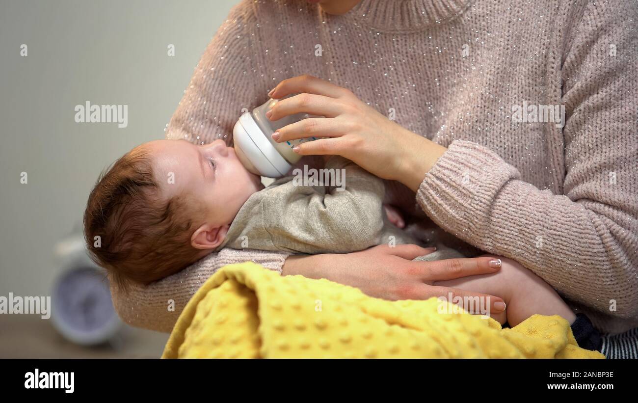 Mamma alimentazione poco simpatici baby dal flacone, teneramente holding figlio, l'amore e la cura Foto Stock