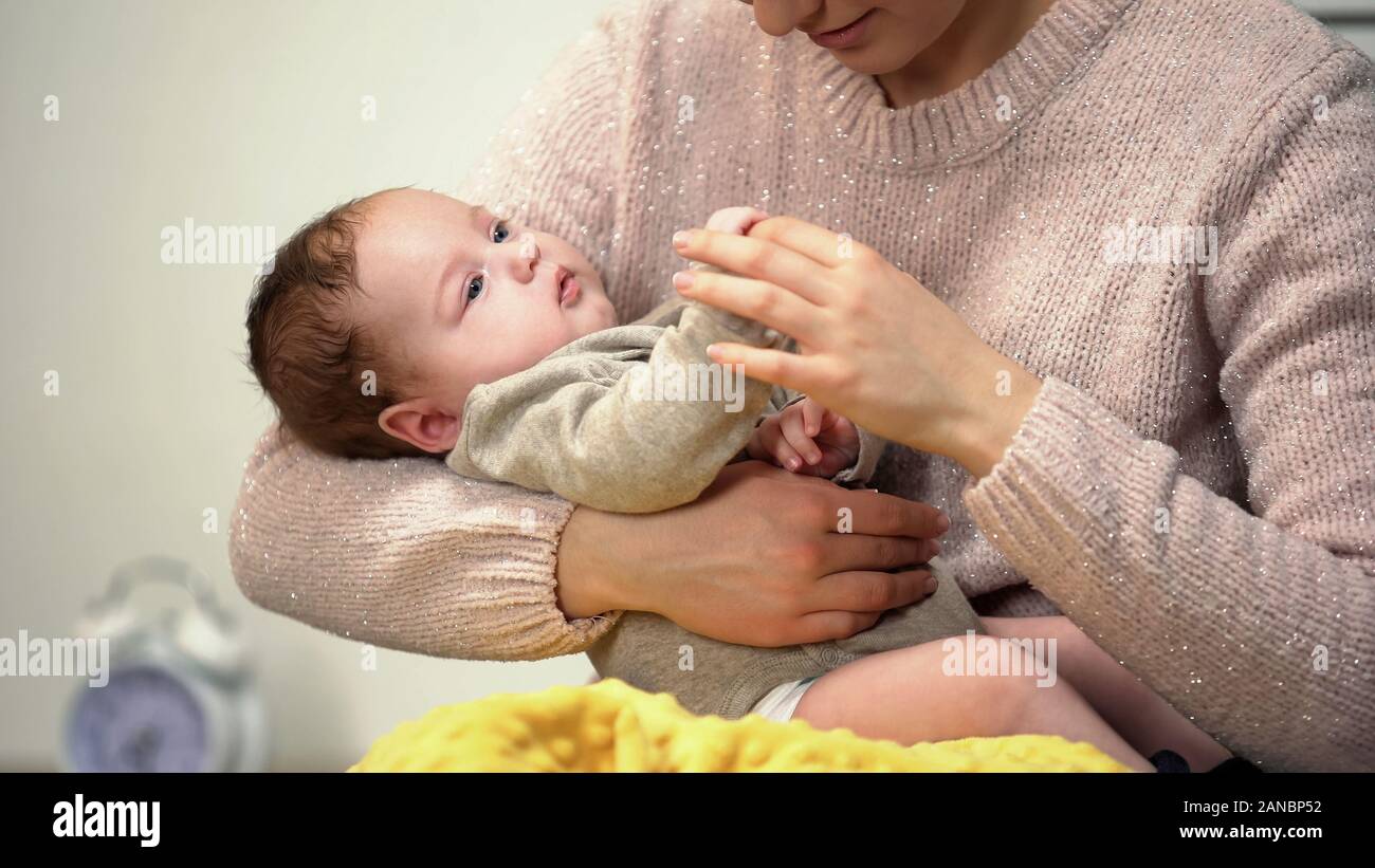 Neonato tenendo le madri dito giacente in madri di bracci, amorevole relazione Foto Stock