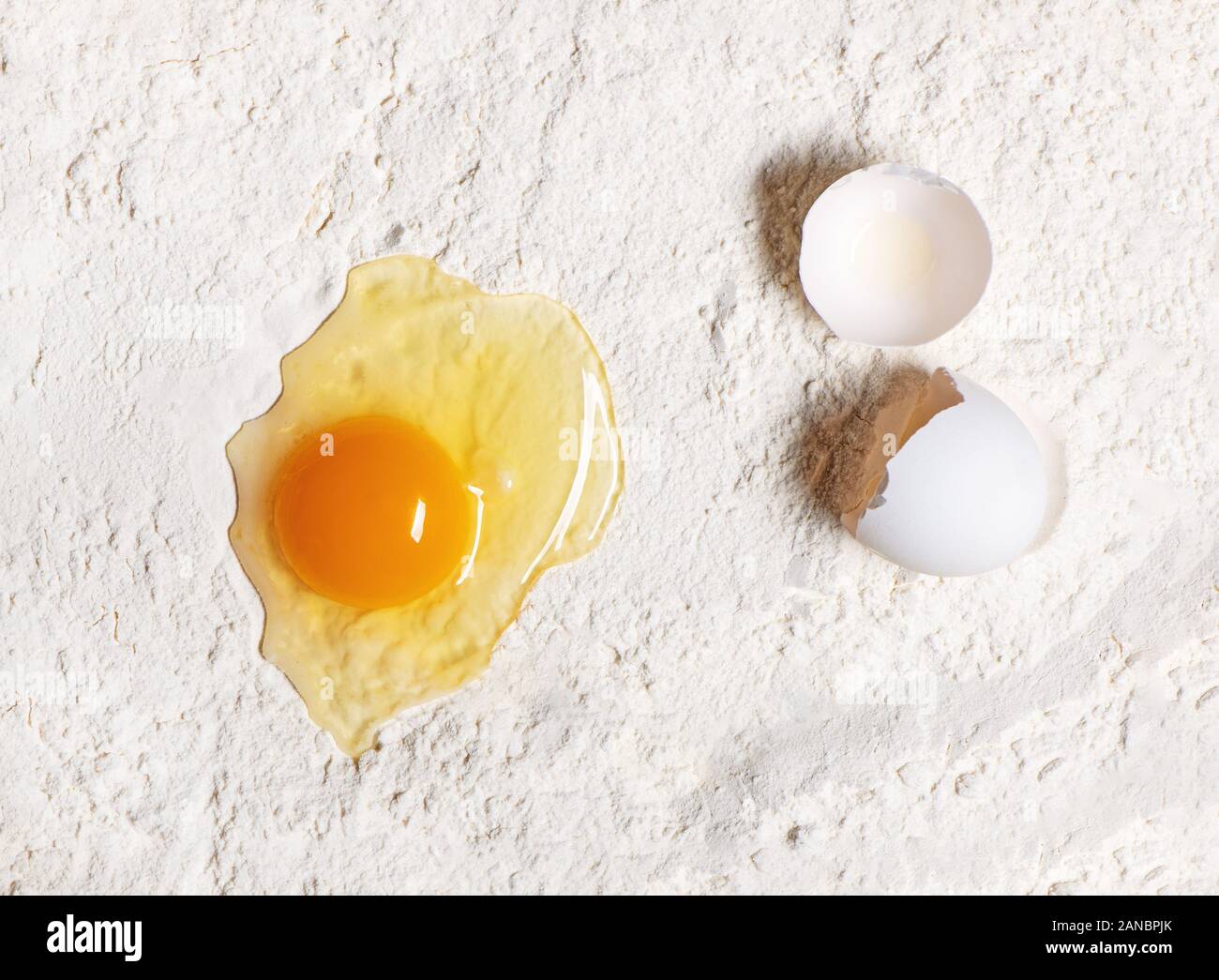 Rotture di uovo crudo sulla farina bianca dello sfondo. Foto Stock