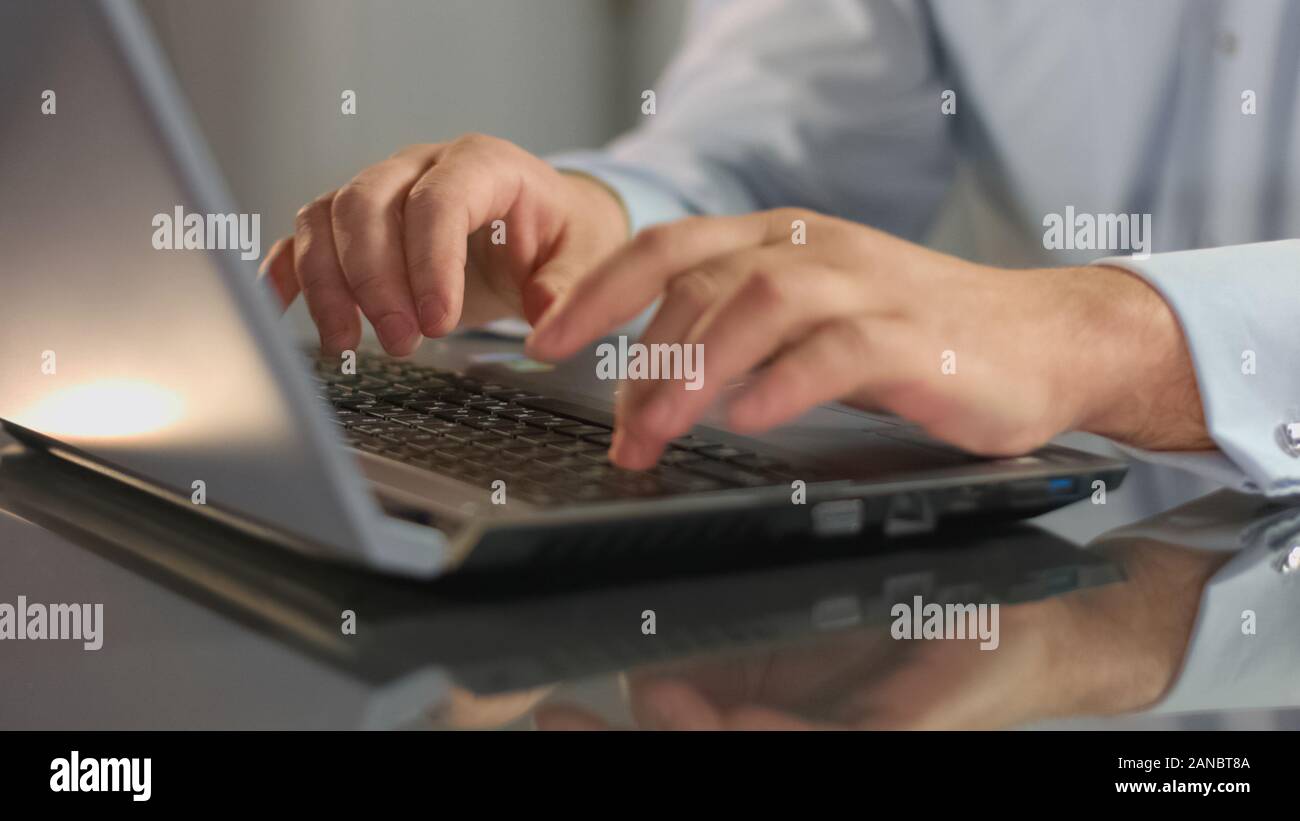 Uomo che lavora in ufficio la digitazione di messaggi di posta elettronica sul computer portatile, preparazione del report, business di avvio Foto Stock