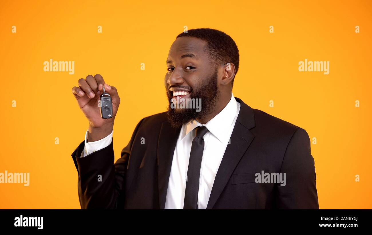 Gioiosa afro-americano in tuta che mostra tasti di automobile, autonoleggi, leasing Foto Stock