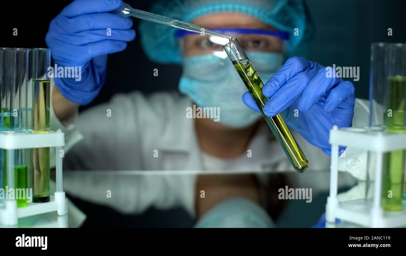 Biologo aggiunta di sostanza oleosa in tubo con pianta verde, estrazione di biocarburanti Foto Stock