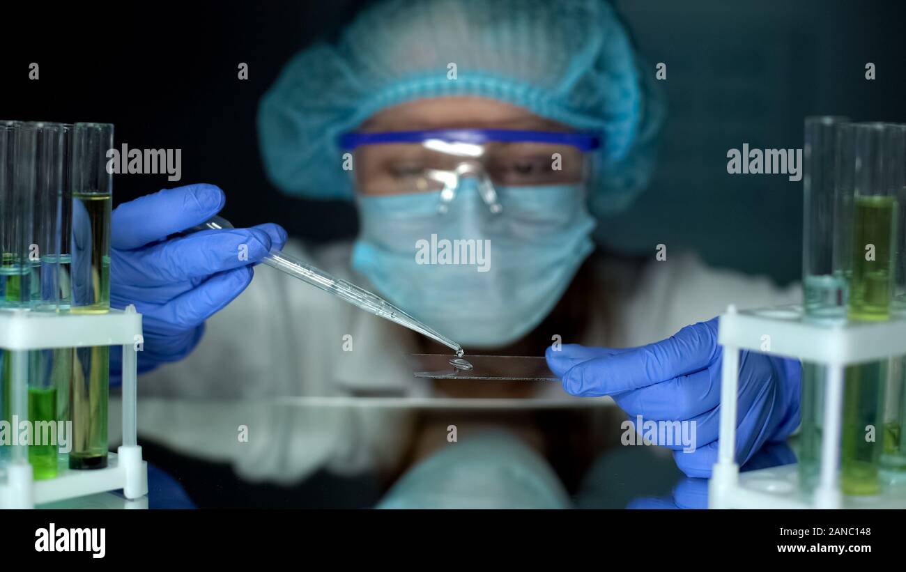 Scienziato di gocciolamento di acqua del campione di prova sul vetro, metalli pesanti analisi di laboratorio, Foto Stock