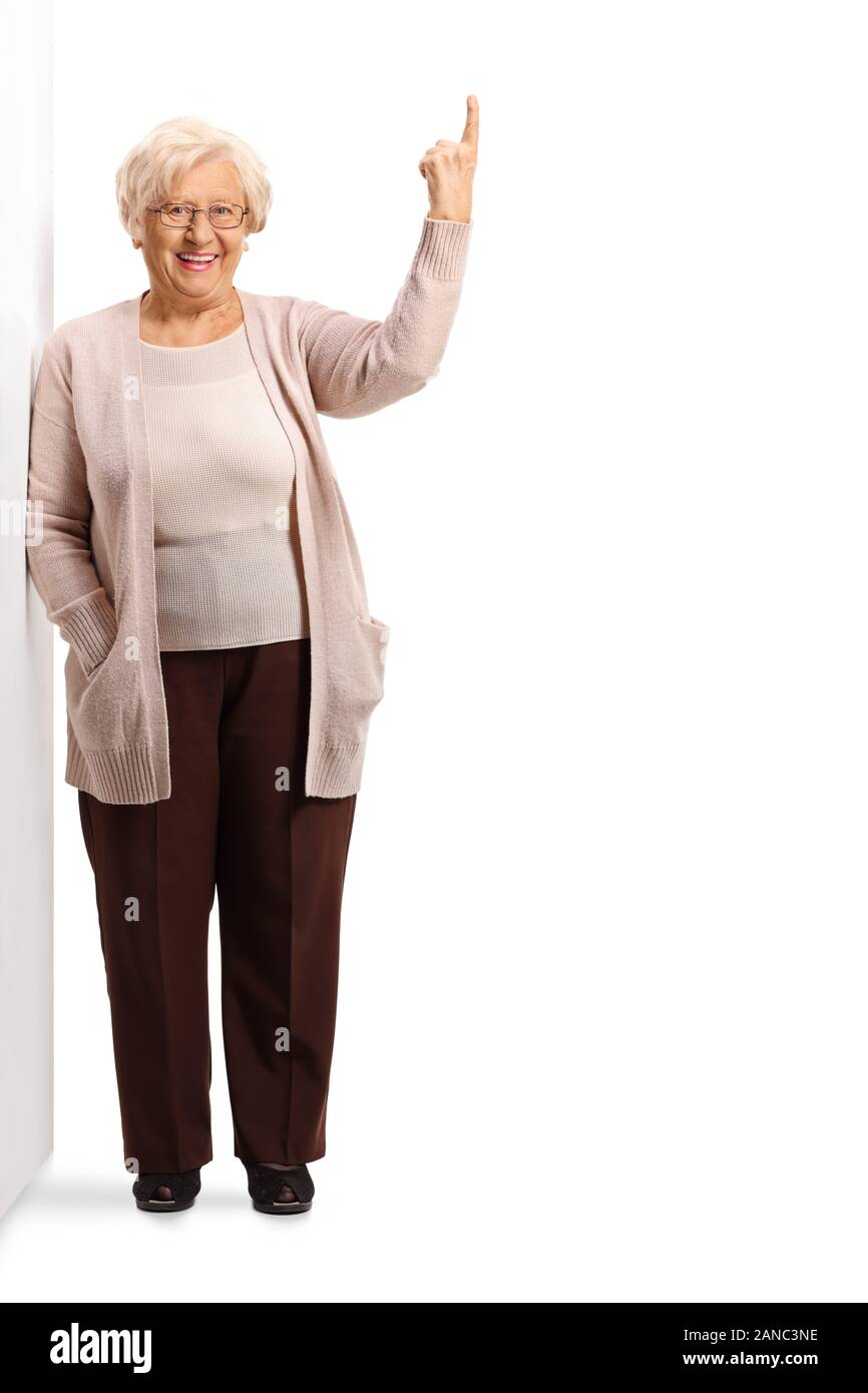 A piena lunghezza Ritratto di una donna anziana appoggiata sulla parete e rivolta verso l'alto al di sopra di segno isolato su sfondo bianco Foto Stock