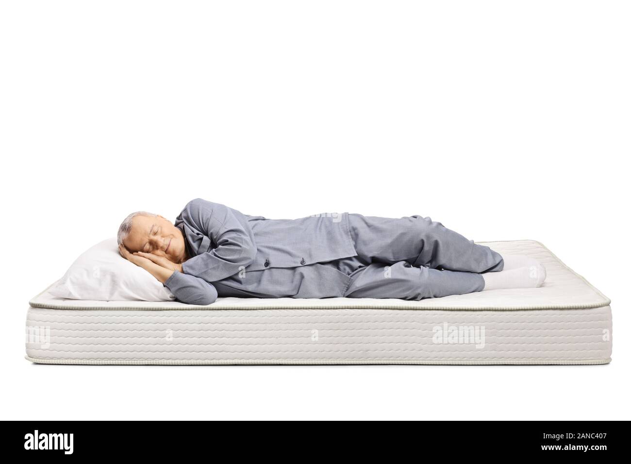 Uomo anziano in pigiama dormire su un letto materasso isolati su sfondo bianco Foto Stock
