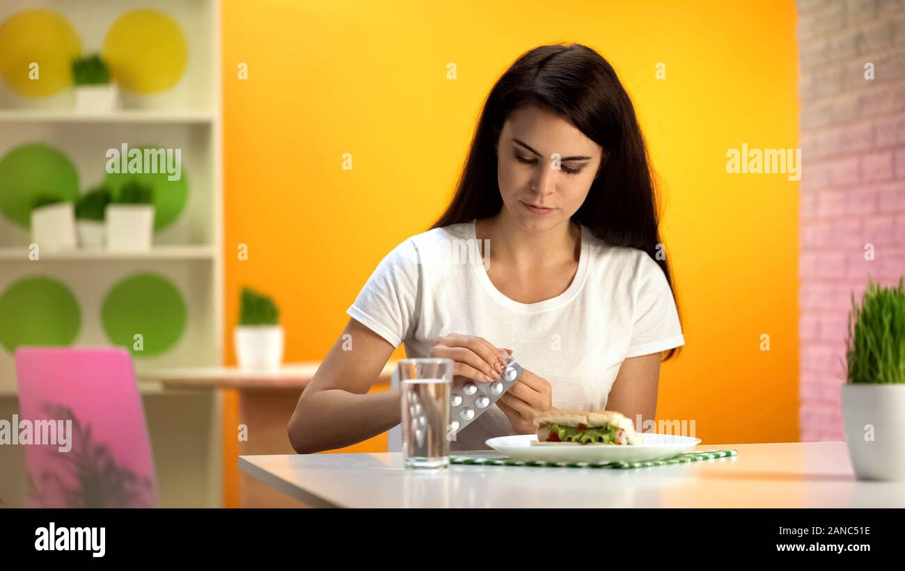 Donna di prendere la medicina dopo ad alto contenuto calorico pasto, bruciori di stomaco malattia, healthcare Foto Stock