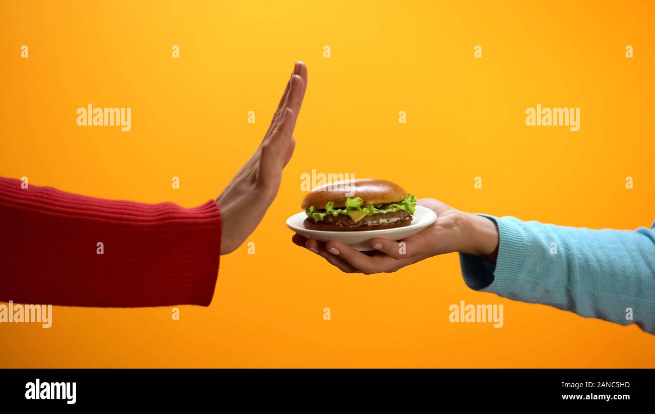 Femmina mostra rifiutare il gesto di burger sulla piastra, fast food restrizione, dieta Foto Stock