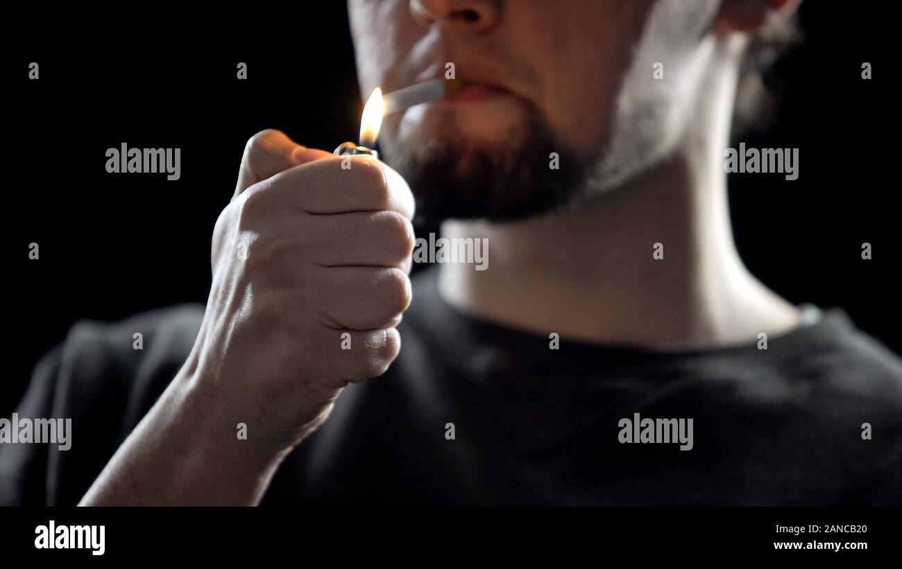 Giovane uomo illuminazione di sigaretta, malsana abitudine, la dipendenza da nicotina closeup Foto Stock