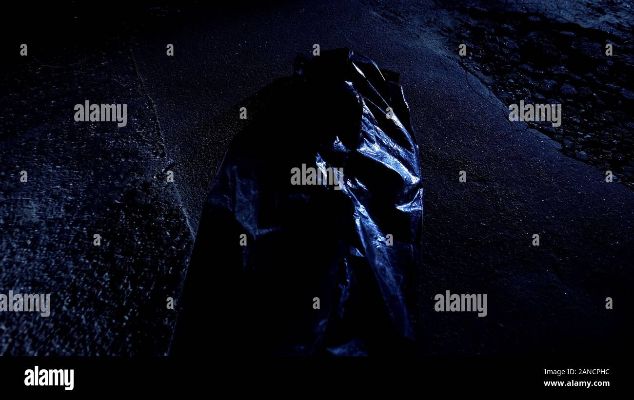 Corpo busta con cadavere giacente su umido asfalto freddo, vittima di omicidio, la scena del crimine Foto Stock