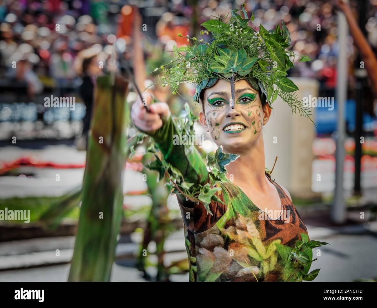 Performer in costume verde dai colori vivaci vestito da pixie con una bacchetta al Flower Parade, Nizza Carnevale, Costa Azzurra, Costa Azzurra, Francia. Foto Stock