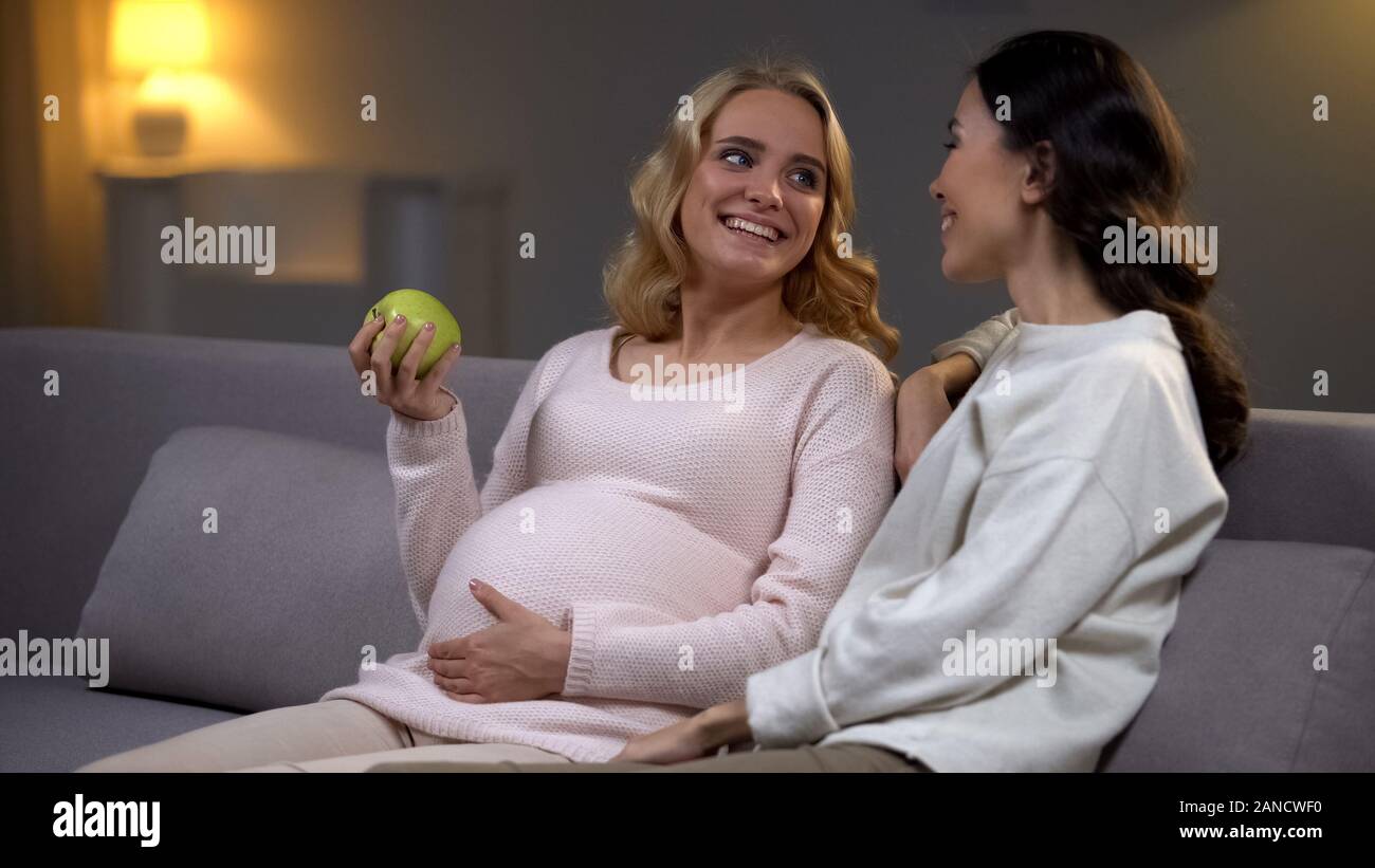 Donna incinta azienda apple parlando con un amico, uno stile di vita sano, maternità Foto Stock
