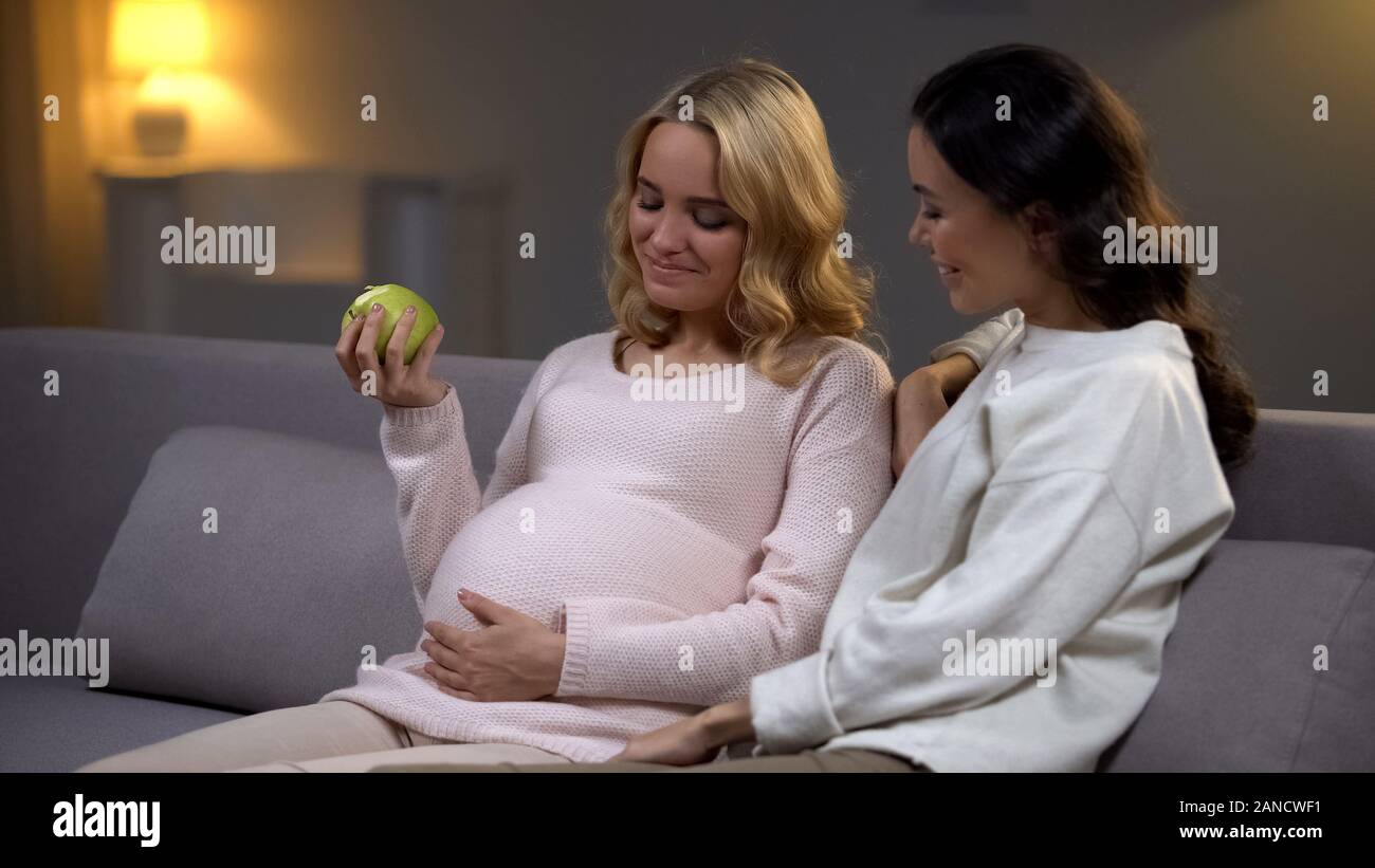 Donna incinta azienda apple parlando con un amico circa la dieta per la salute del bambino Foto Stock