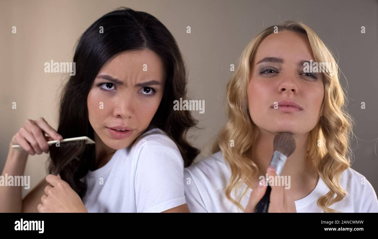 Due ragazze di applicare il make up, lottando per il posto di fronte a specchio, rivalità, invidia Foto Stock