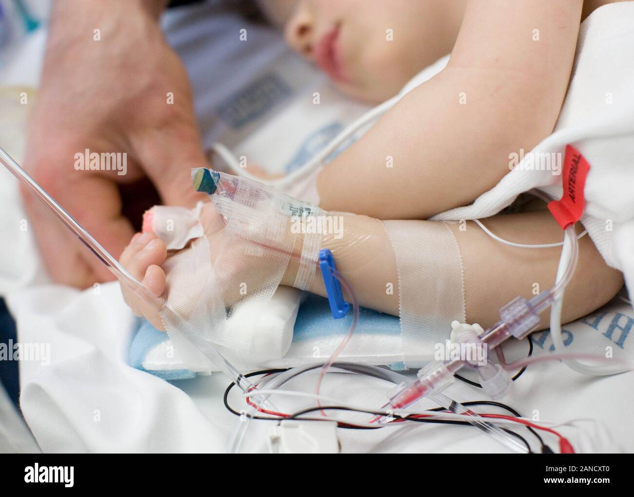 Padre che tiene la mano del bambino in ospedale collegato a IV, pulse bue Foto Stock
