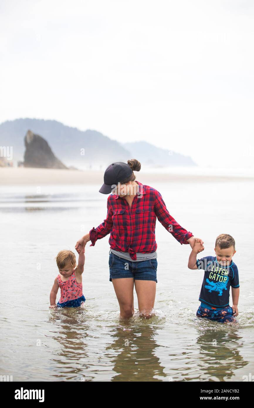 La madre si guadi attraverso l'acqua con i suoi due figli. Foto Stock