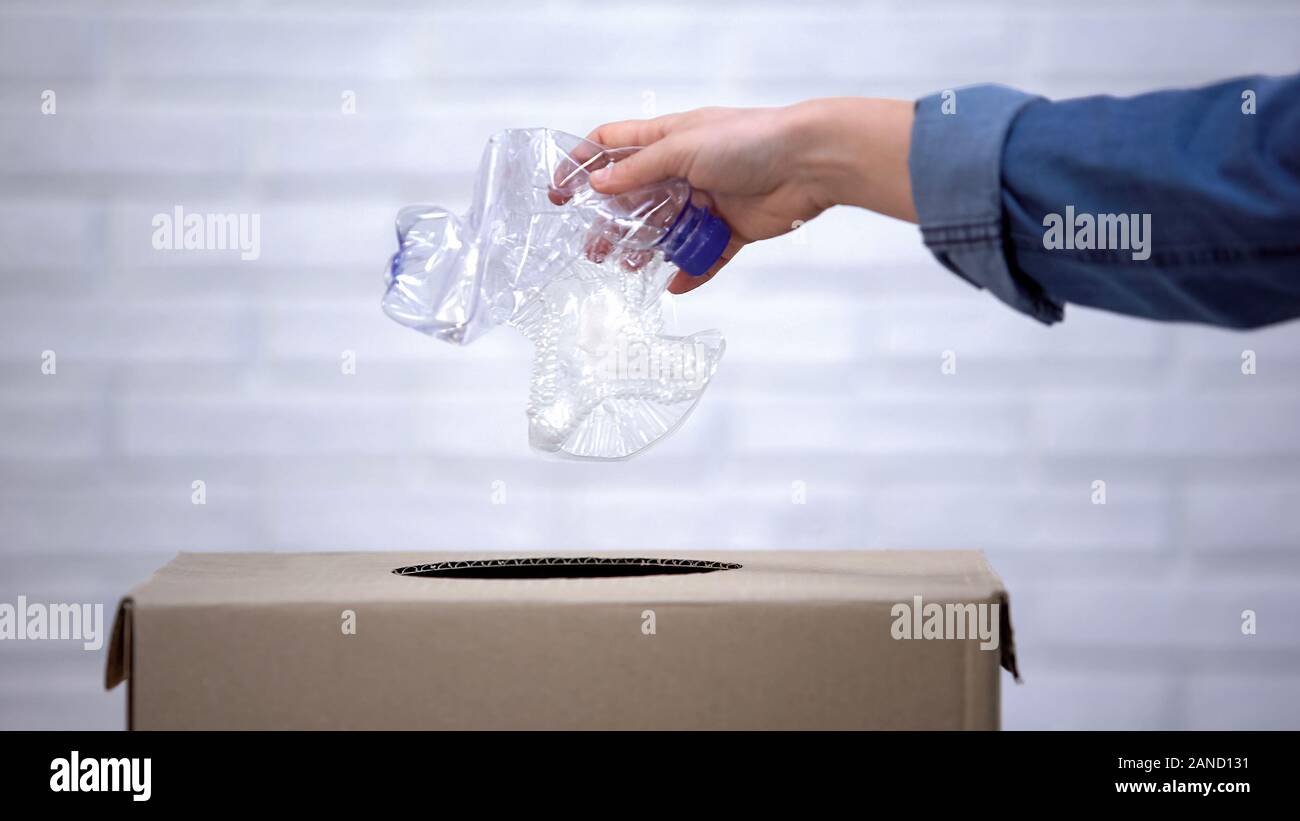 La mano di gettare le bottiglie di plastica nel cestino della spazzatura, ordinamento non degradabili in rifiuti Foto Stock