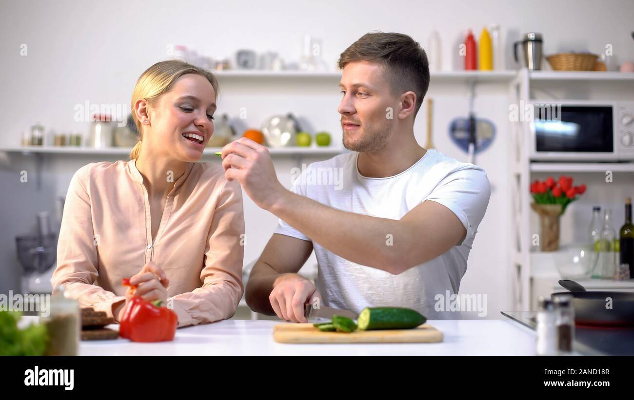 Divertente carino coppia flirt, marito, moglie di alimentazione con verdure crude, alimenti eco Foto Stock