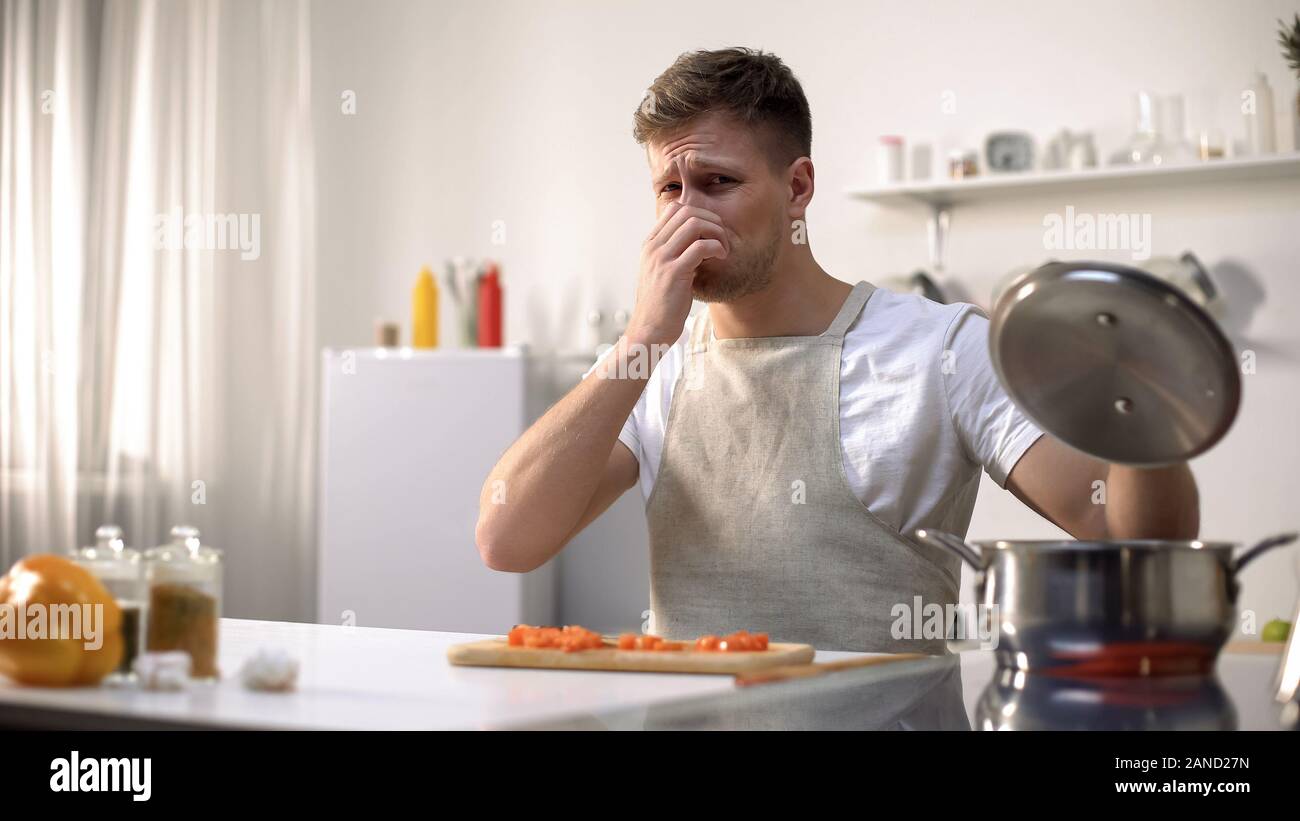 Corso di laurea preparati untasty zuppa, disgustato con odore di pasto, debuttante chef Foto Stock