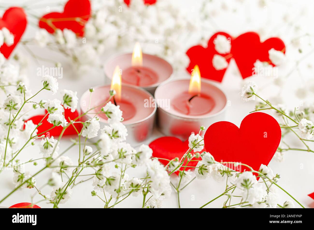 Romantico Sfondo San Valentino. Candele accese e cuori rossi decorati con  fiori bianchi Foto stock - Alamy