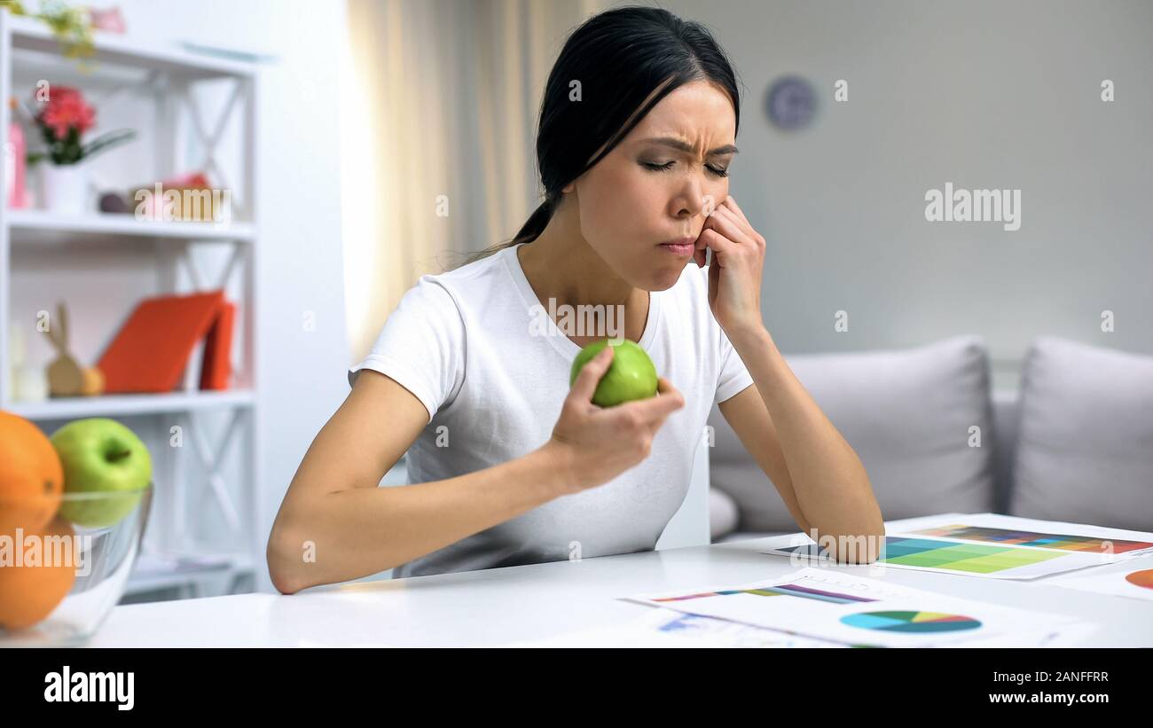 I giovani designer sensazione di dolore dentale azienda mela verde, lavorano a casa, salute Foto Stock