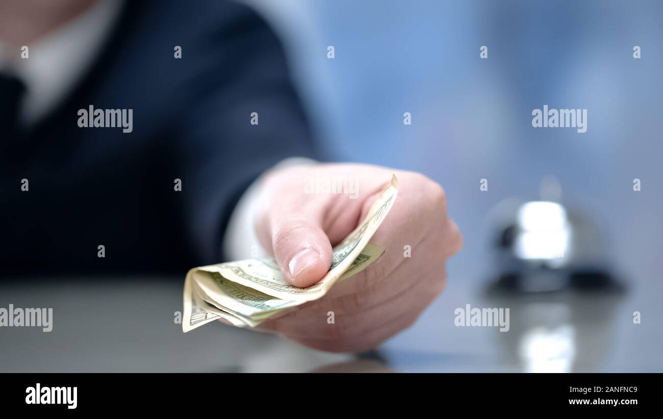 Maschio lato dà soldi presso la reception dell'hotel, pagando per viaggio di affari alloggio Foto Stock