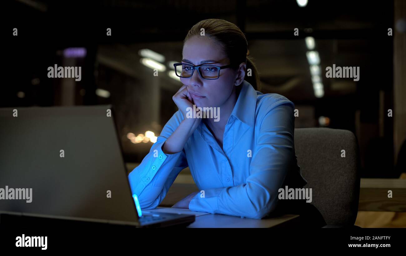 Giovane donna annoiato lavora al computer in ufficio, esaurito e immotivato Foto Stock
