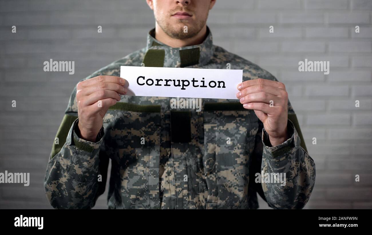 La corruzione parola scritta sul segno nelle mani del soldato maschio, industria della difesa la criminalità Foto Stock