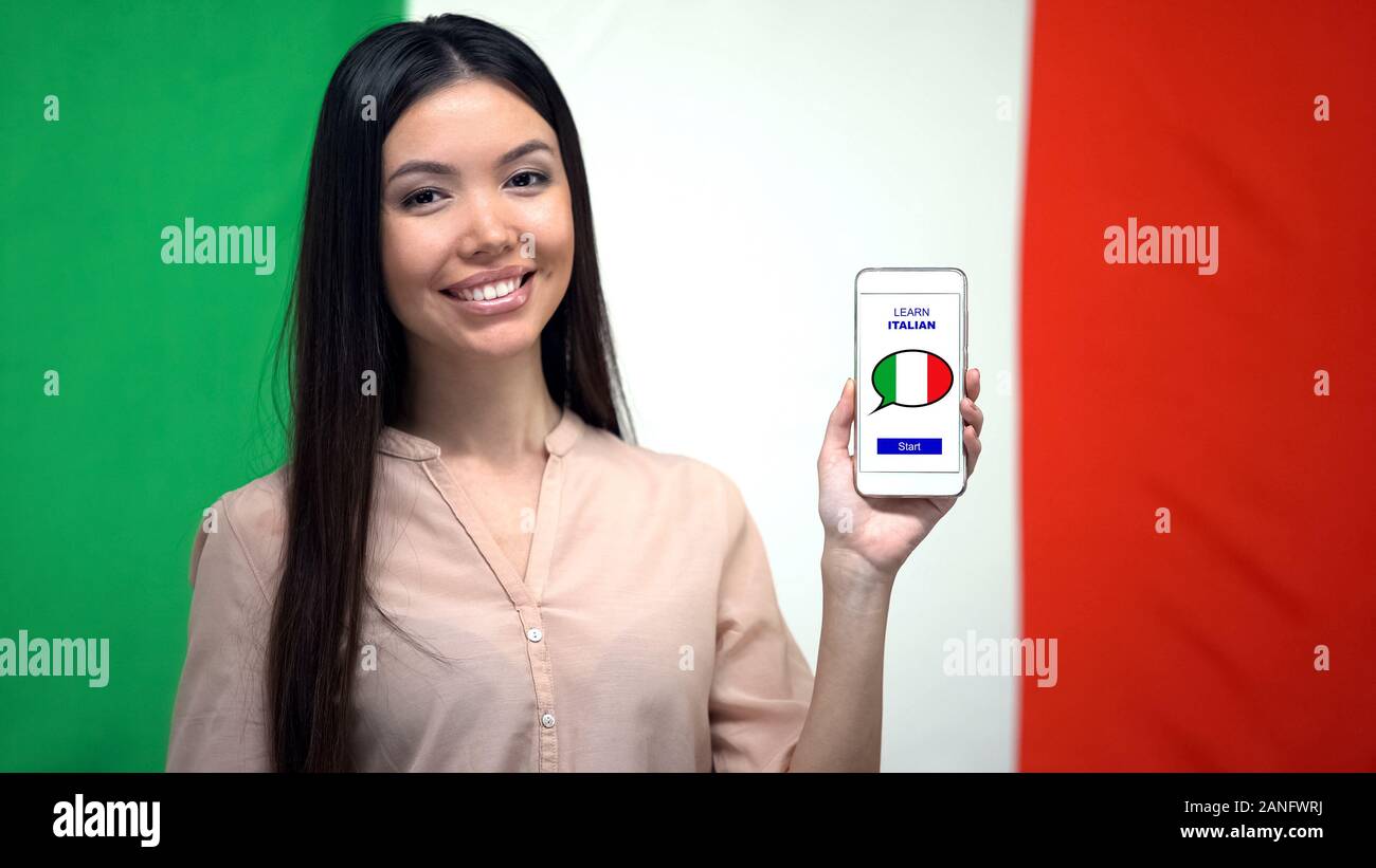 Signora che mostra il cellulare con imparare italiano app, bandiera su sfondo, istruzione Foto Stock