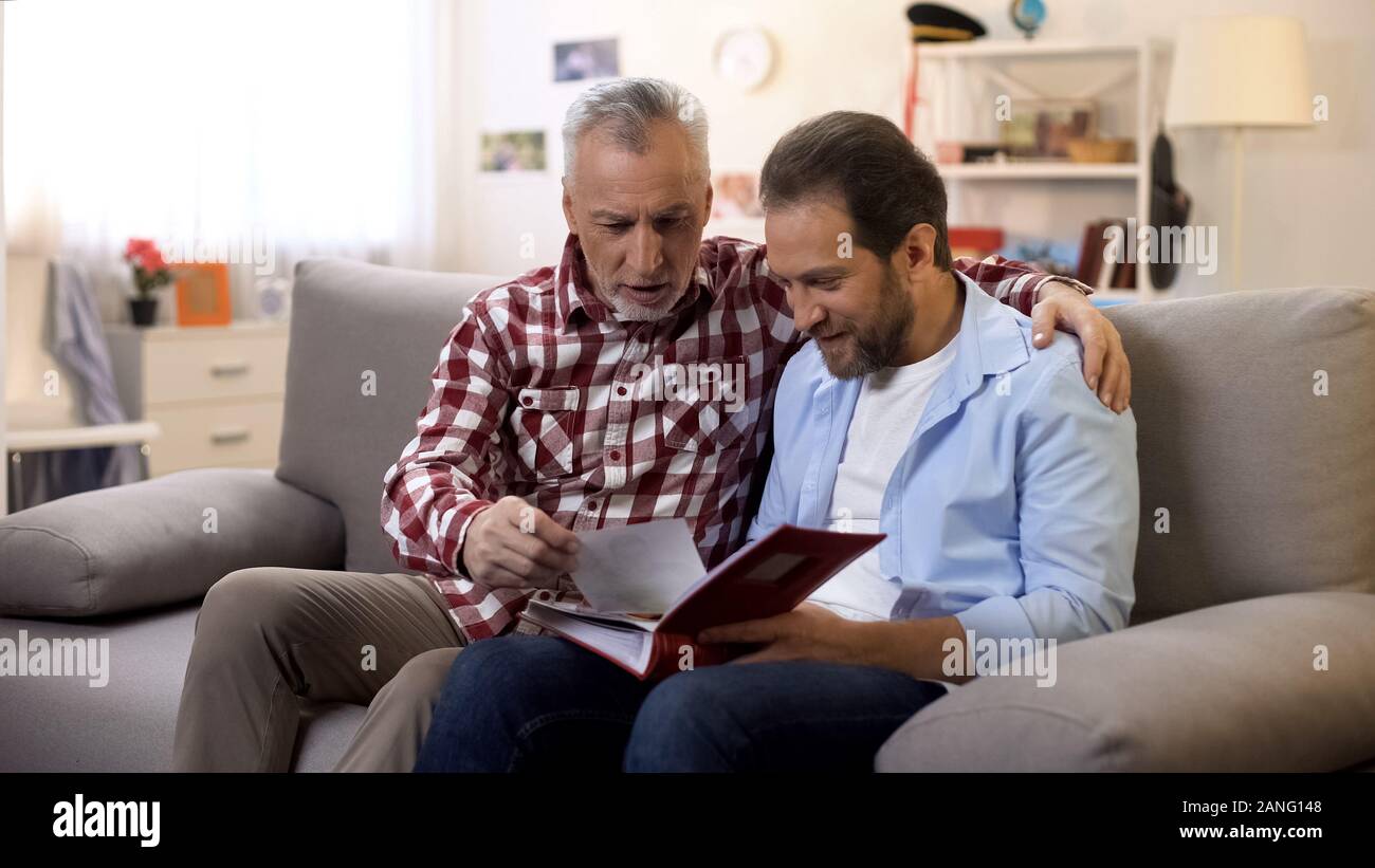 Adulto padre e figlio la visualizzazione di vecchie foto di condivisione di buone memorie tradizioni di famiglia Foto Stock