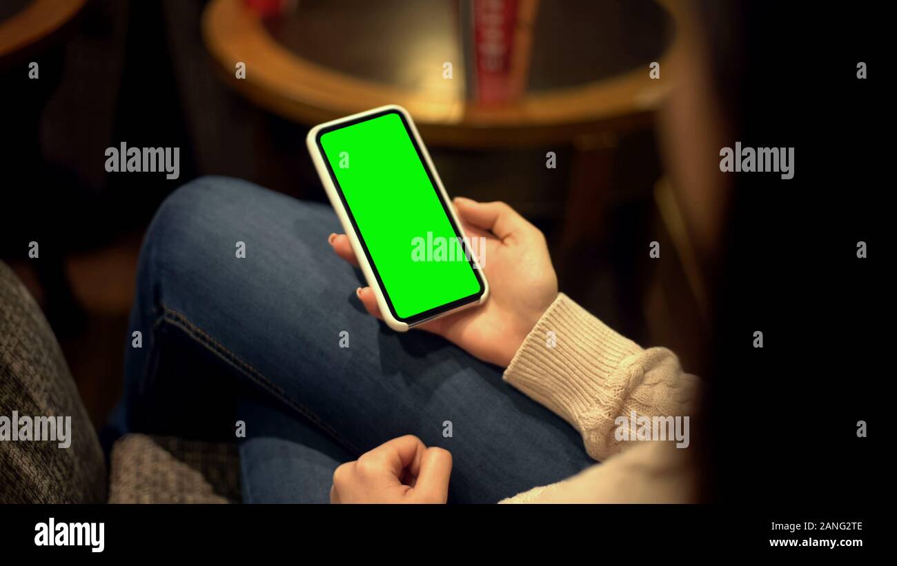 Donna che mantiene lo smartphone con lo schermo verde, luogo di annuncio, alfa modello di canale Foto Stock