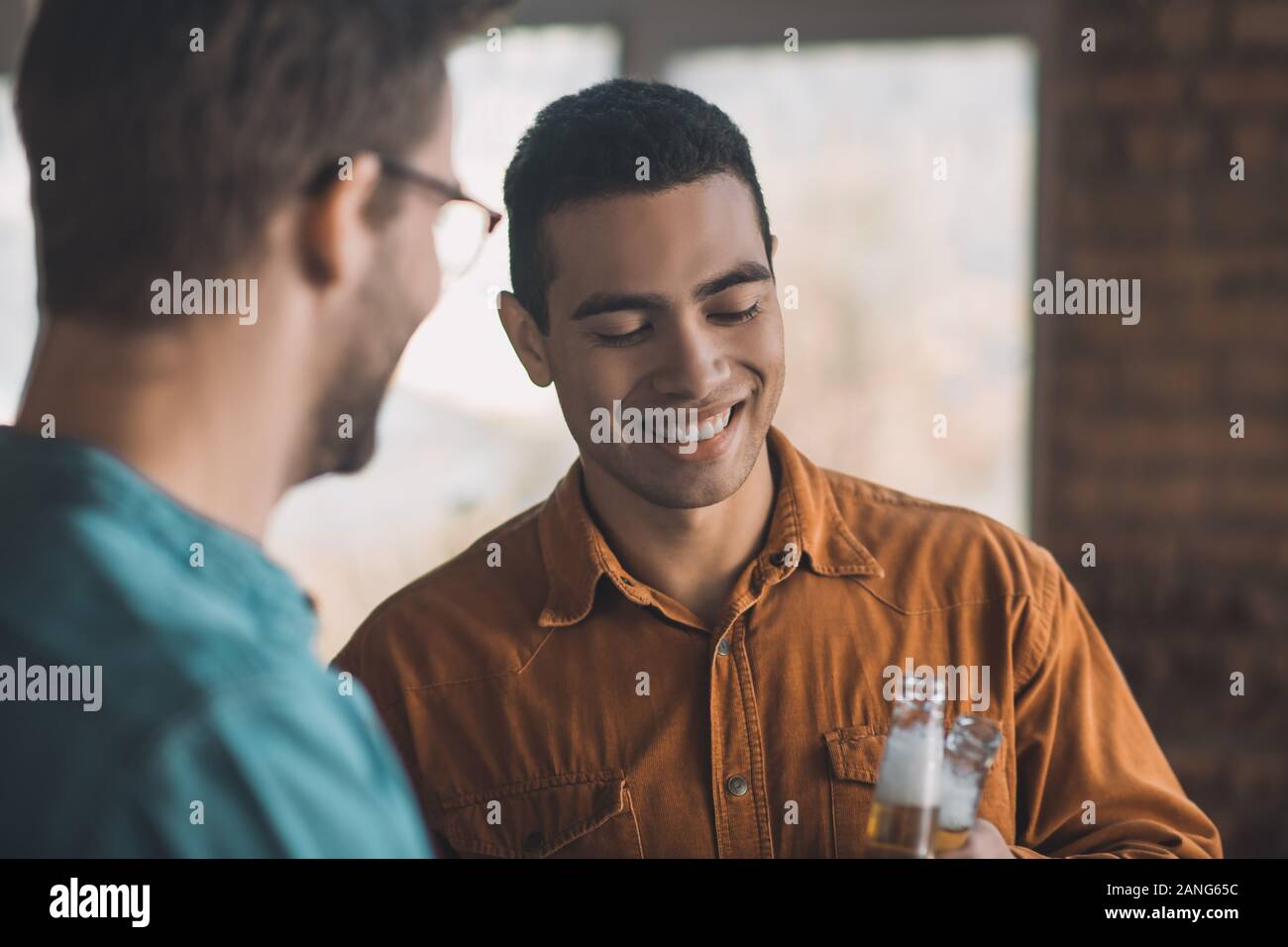 Gioioso uomo positivo di bere birra con il suo amico Foto Stock