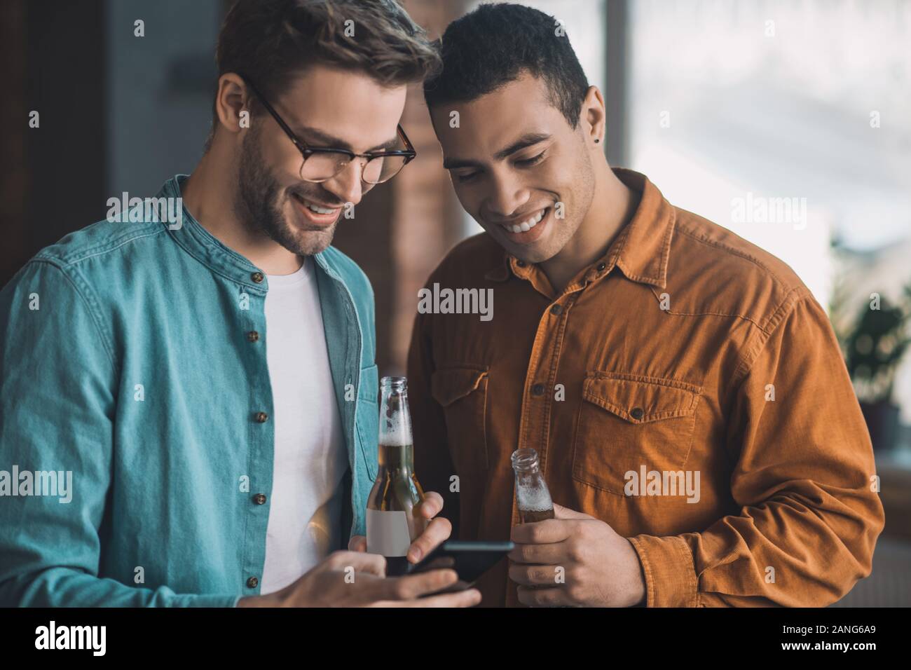 Allegro positivo gli uomini guardando insieme a lo schermo dello smartphone Foto Stock