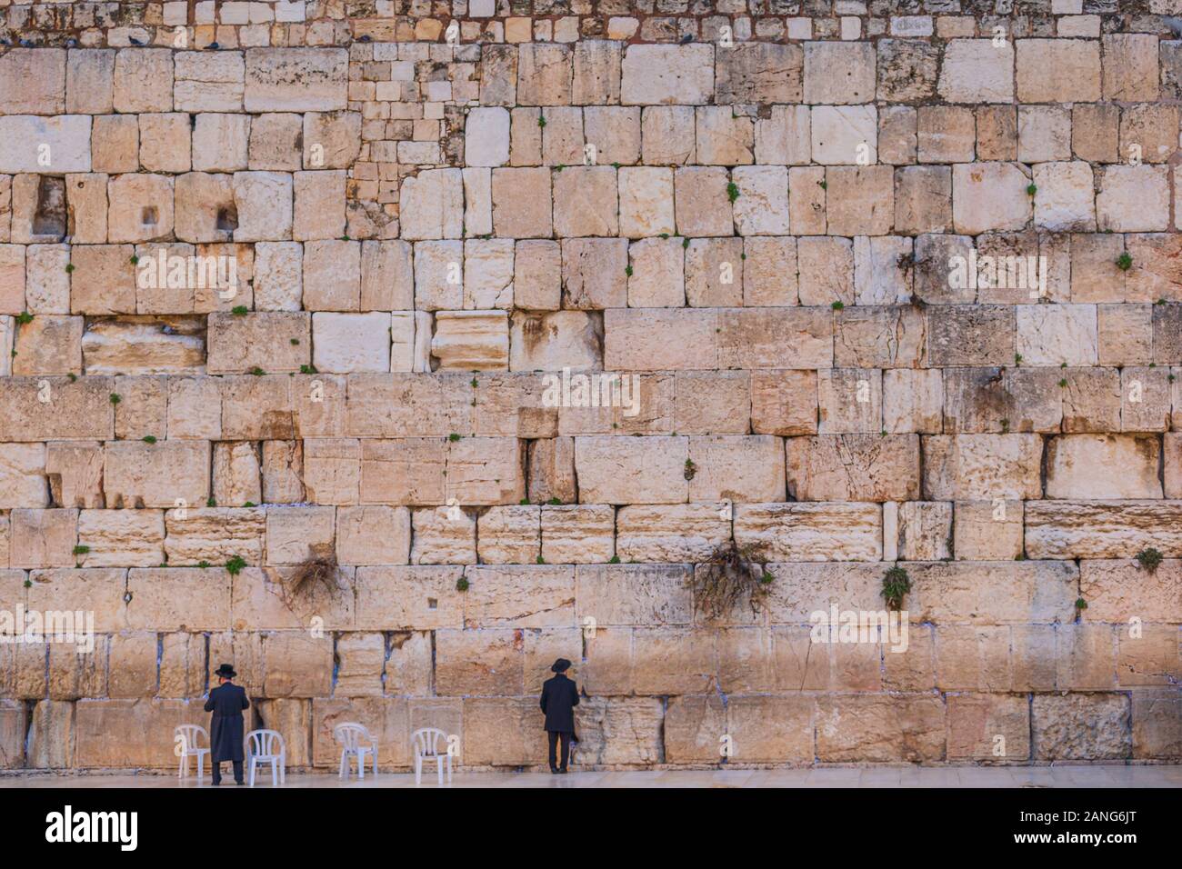 Un enorme muro occidentale con piccoli esseri umani pregando - Gerusalemme, Israele Foto Stock